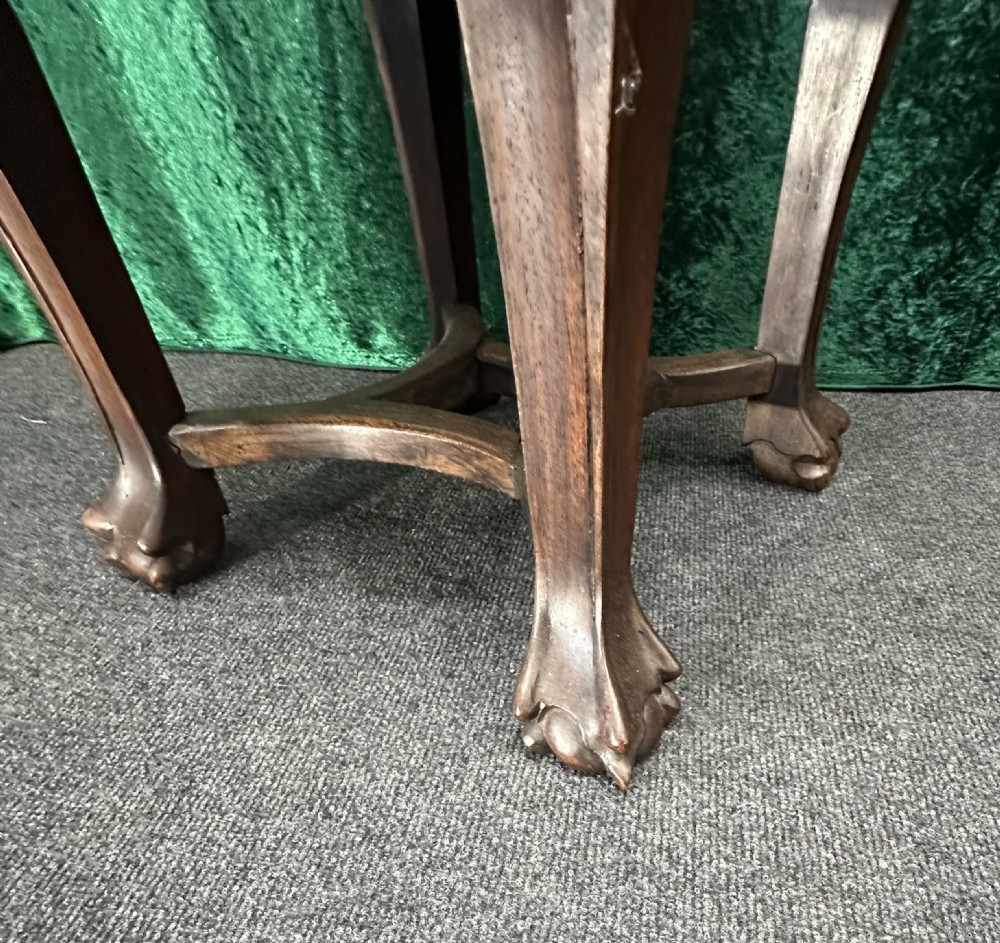 A dark carved padouk wood hexagonal stand featuring an inset marble top, pierced foliage apron, and cabriole legs. View VII