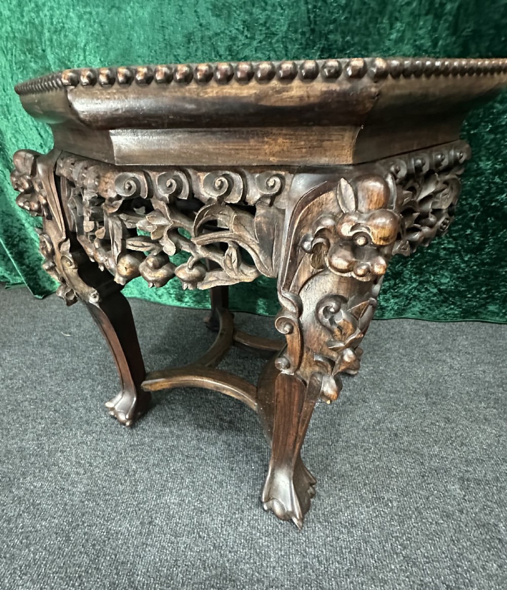 A dark carved padouk wood hexagonal stand featuring an inset marble top, pierced foliage apron, and cabriole legs. View VIII