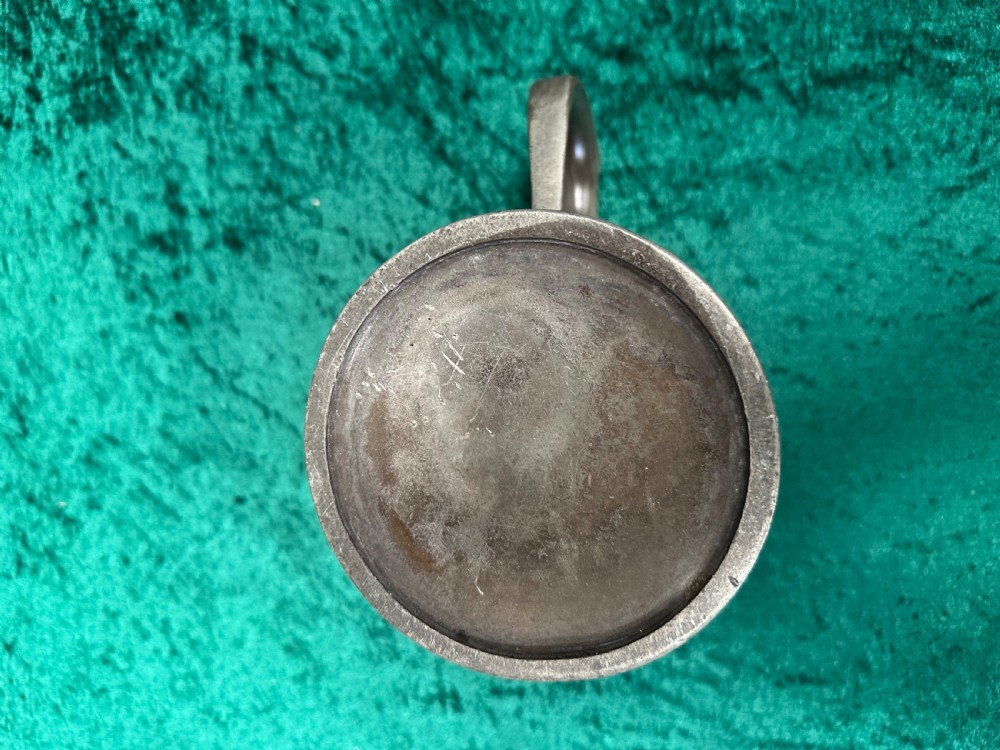 A Victorian pewter quart measure featuring a curved handle, horizontal body mouldings, and a brass rim stamped with capacity verification marks. View VI