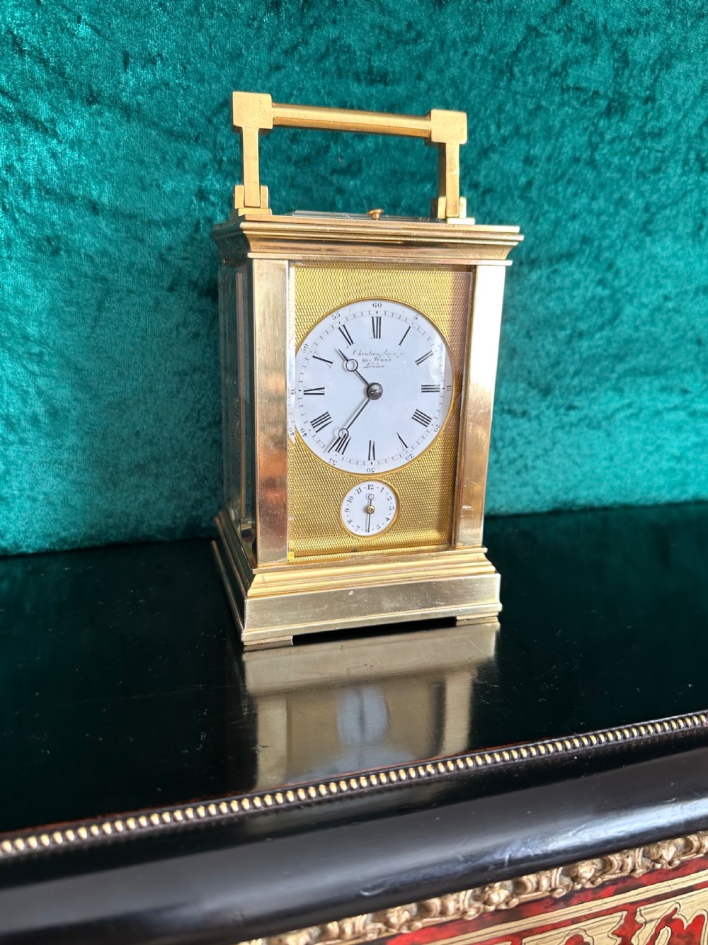 A late 19th-century gilt brass French carriage clock featuring a rectangular case, top carrying handle, glass panels revealing internal gears, and a white enamel dial with Roman numerals. View II