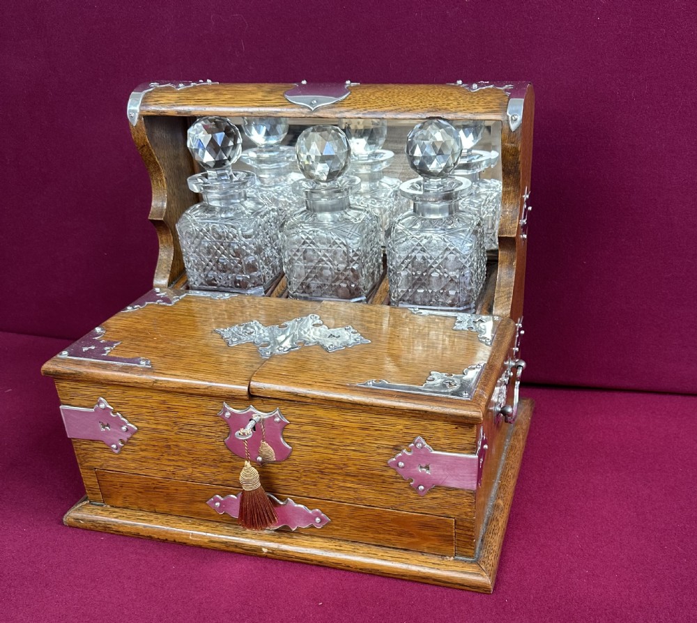 An open Edwardian oak games compendium displaying three cut crystal decanters, chess pieces, cribbage board, dominoes, and playing cards. View II