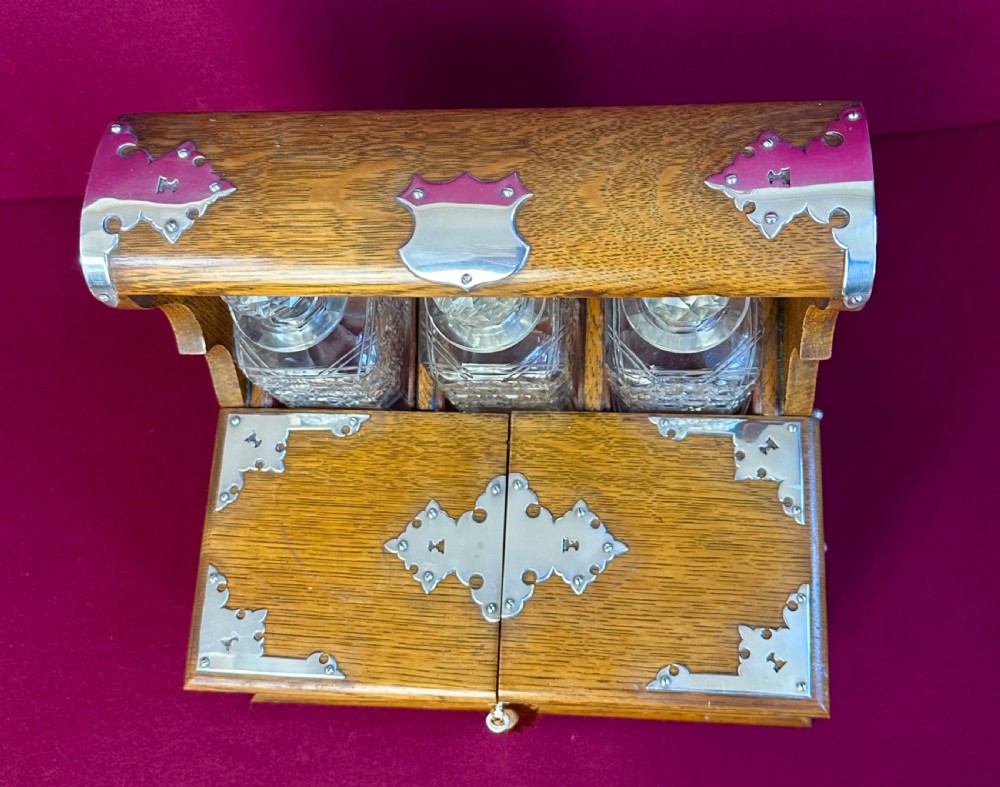 An open Edwardian oak games compendium displaying three cut crystal decanters, chess pieces, cribbage board, dominoes, and playing cards. View III