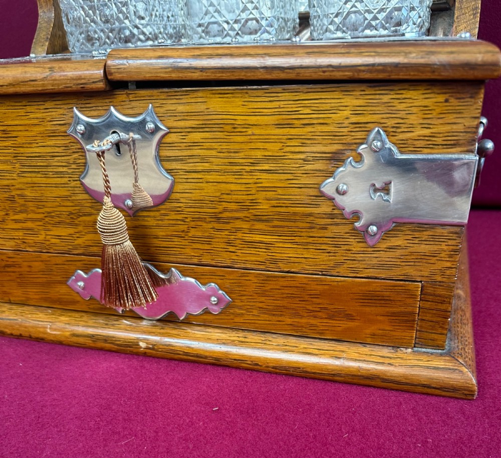 An open Edwardian oak games compendium displaying three cut crystal decanters, chess pieces, cribbage board, dominoes, and playing cards. View V