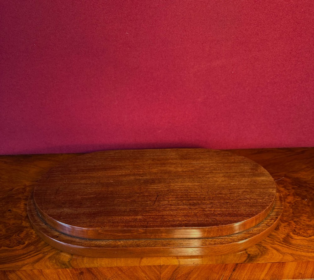 A clear, mouth-blown oval glass dome featuring a rounded top resting on a dark moulded wooden plinth. View III