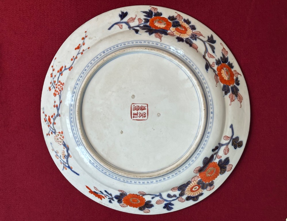 A circular Japanese Imari porcelain charger decorated with cobalt blue, iron red, and orange floral motifs around a central urn pattern. View II