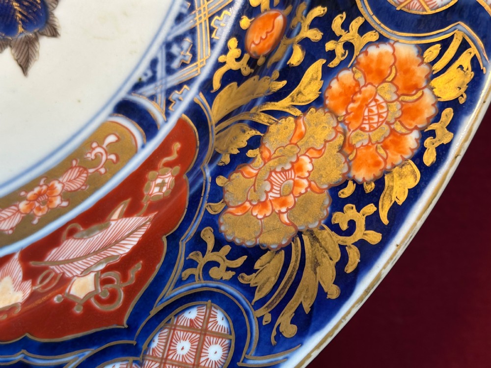 A circular Japanese Imari porcelain charger decorated with cobalt blue, iron red, and orange floral motifs around a central urn pattern. View VI