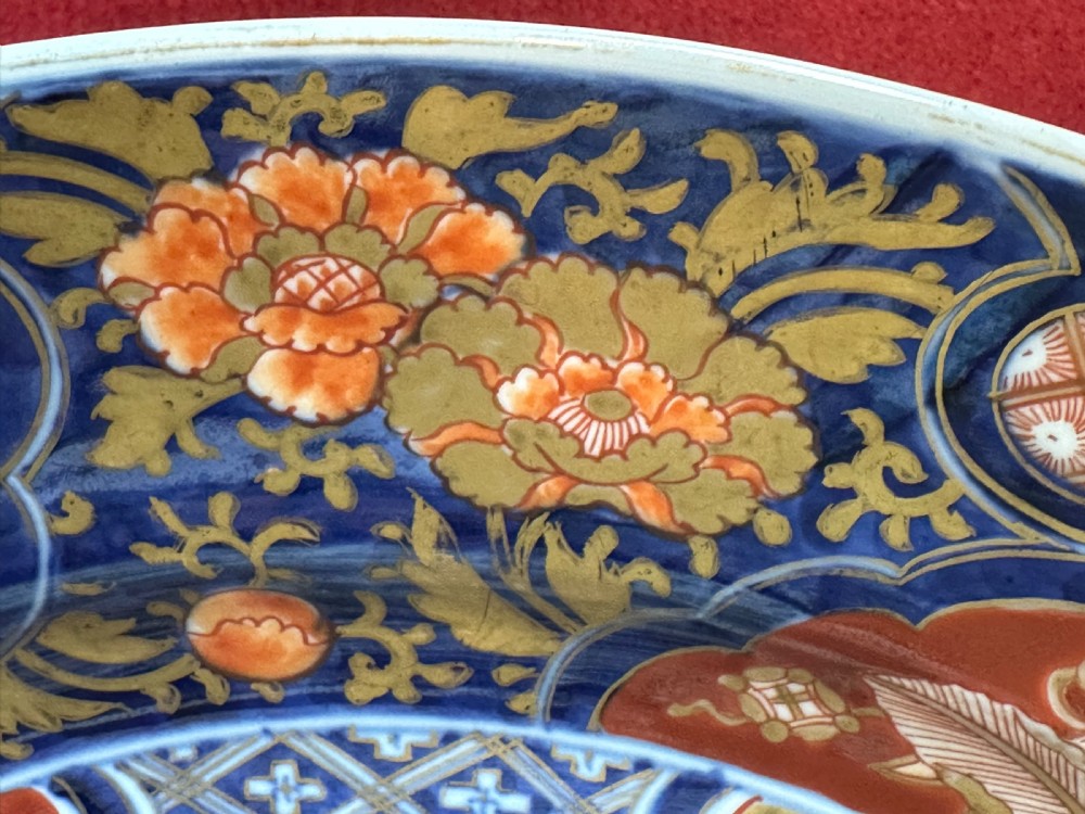 A circular Japanese Imari porcelain charger decorated with cobalt blue, iron red, and orange floral motifs around a central urn pattern. View VII