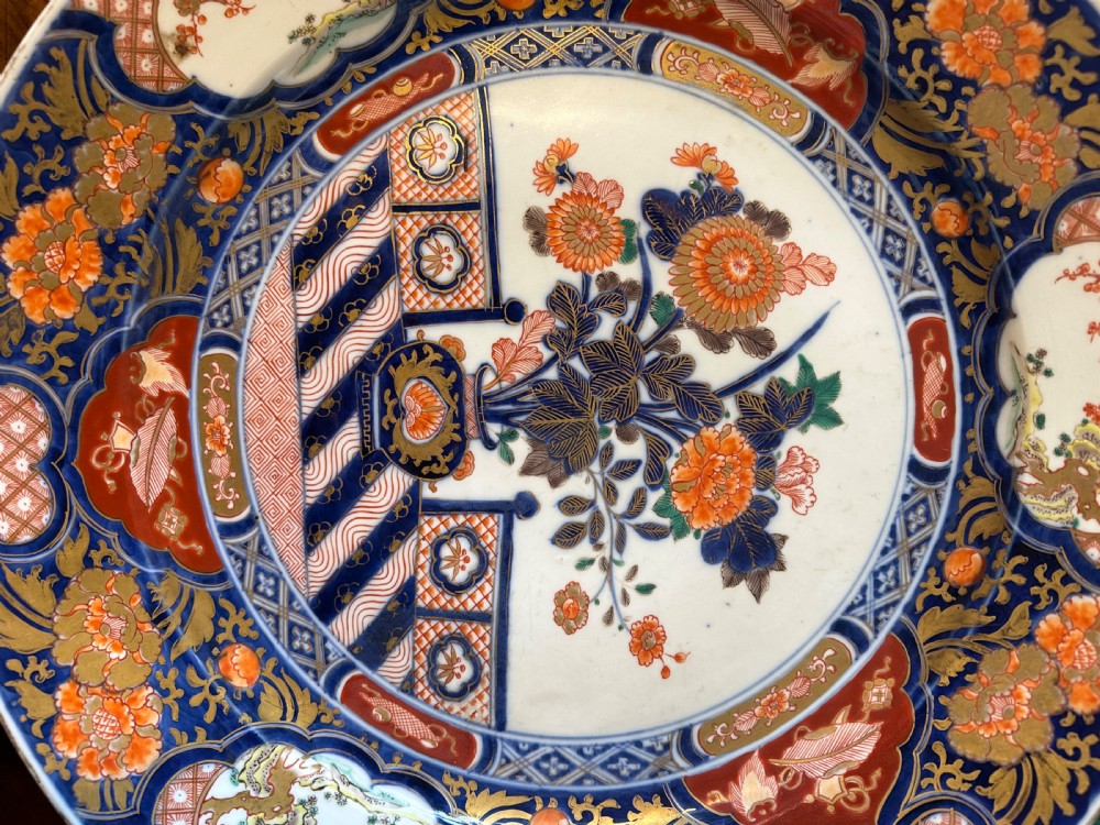 A circular Japanese Imari porcelain charger decorated with cobalt blue, iron red, and orange floral motifs around a central urn pattern. View VIII