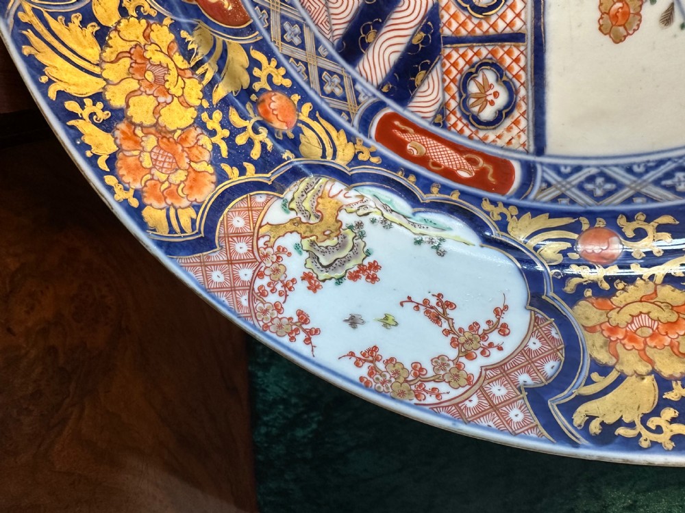 A circular Japanese Imari porcelain charger decorated with cobalt blue, iron red, and orange floral motifs around a central urn pattern. View IX