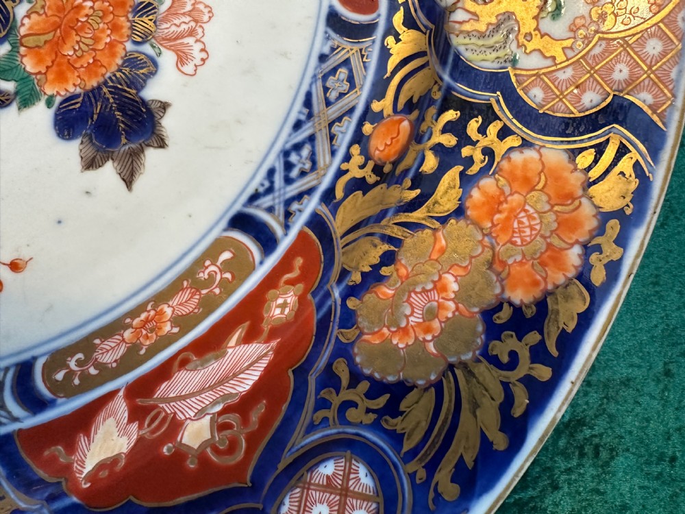 A circular Japanese Imari porcelain charger decorated with cobalt blue, iron red, and orange floral motifs around a central urn pattern. View XI