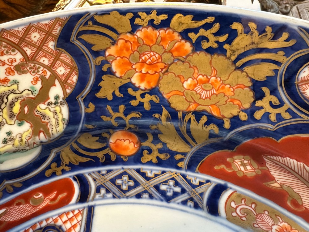 A circular Japanese Imari porcelain charger decorated with cobalt blue, iron red, and orange floral motifs around a central urn pattern. View XII