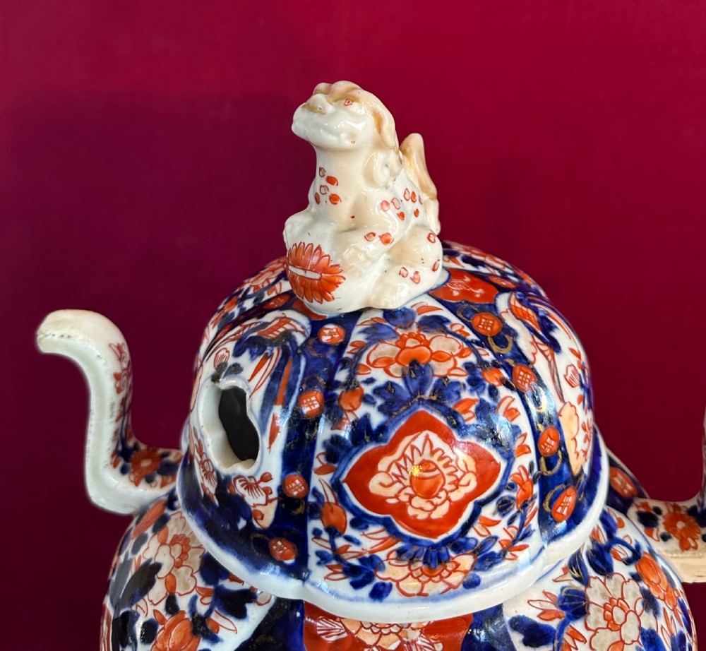 A Japanese Imari porcelain koro incense burner featuring a pierced domed lid topped with a shishi lion finial, twin side handles, tripod feet, and hand-painted blue and iron-red panels. View V