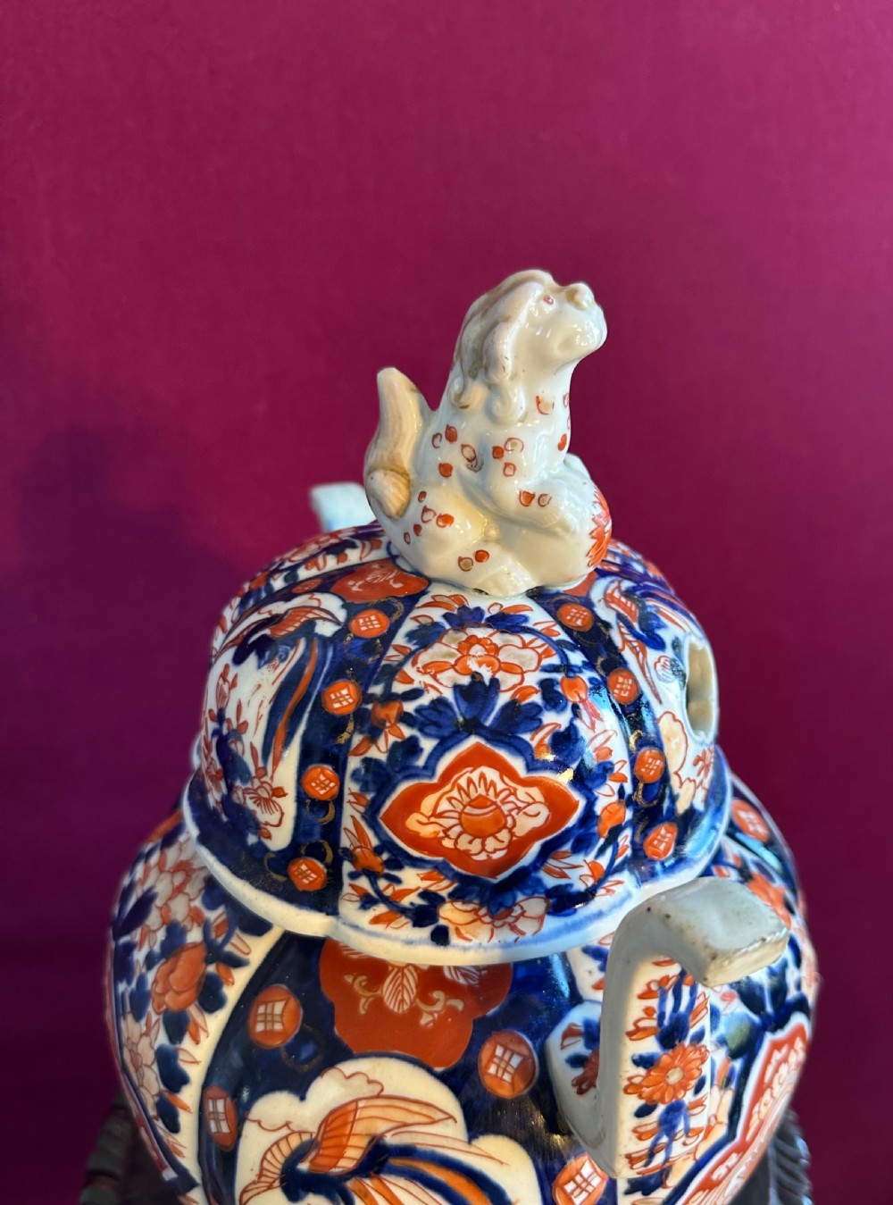 A Japanese Imari porcelain koro incense burner featuring a pierced domed lid topped with a shishi lion finial, twin side handles, tripod feet, and hand-painted blue and iron-red panels. View VI