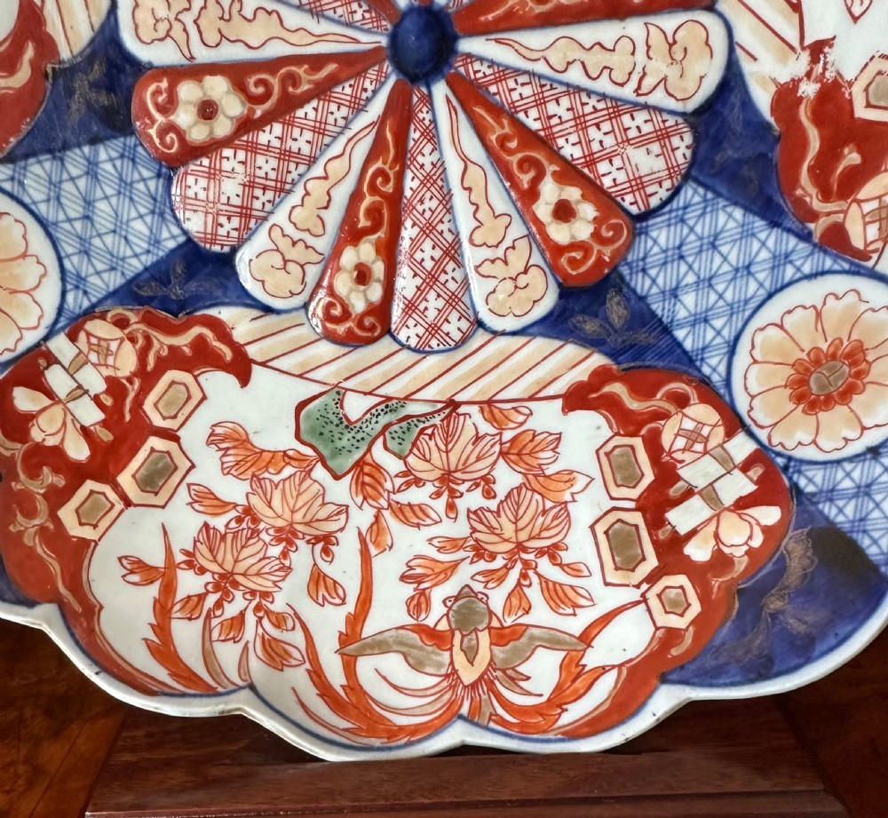 A pair of circular Japanese Imari porcelain chargers with scalloped edges, featuring intricate floral panels in cobalt blue, rust red, and white. View II
