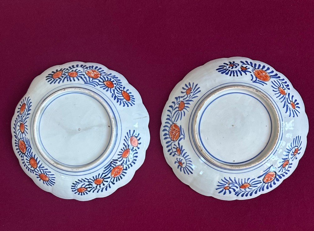 A pair of circular Japanese Imari porcelain chargers with scalloped edges, featuring intricate floral panels in cobalt blue, rust red, and white. View VII