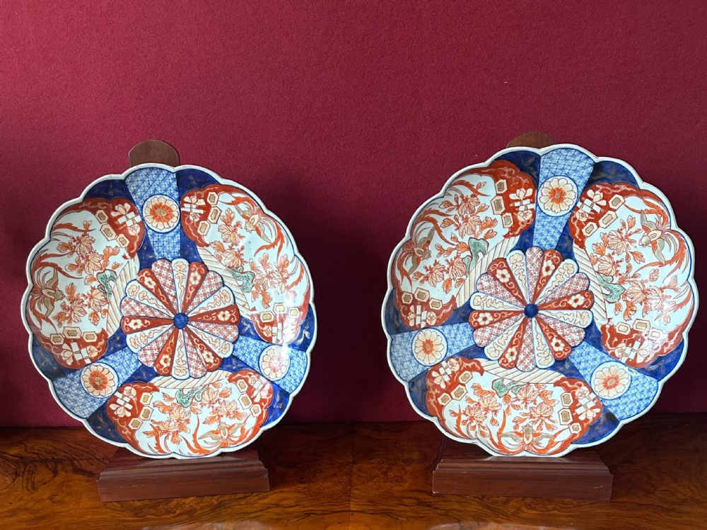 A pair of circular Japanese Imari porcelain chargers with scalloped edges, featuring intricate floral panels in cobalt blue, rust red, and white. View VIII