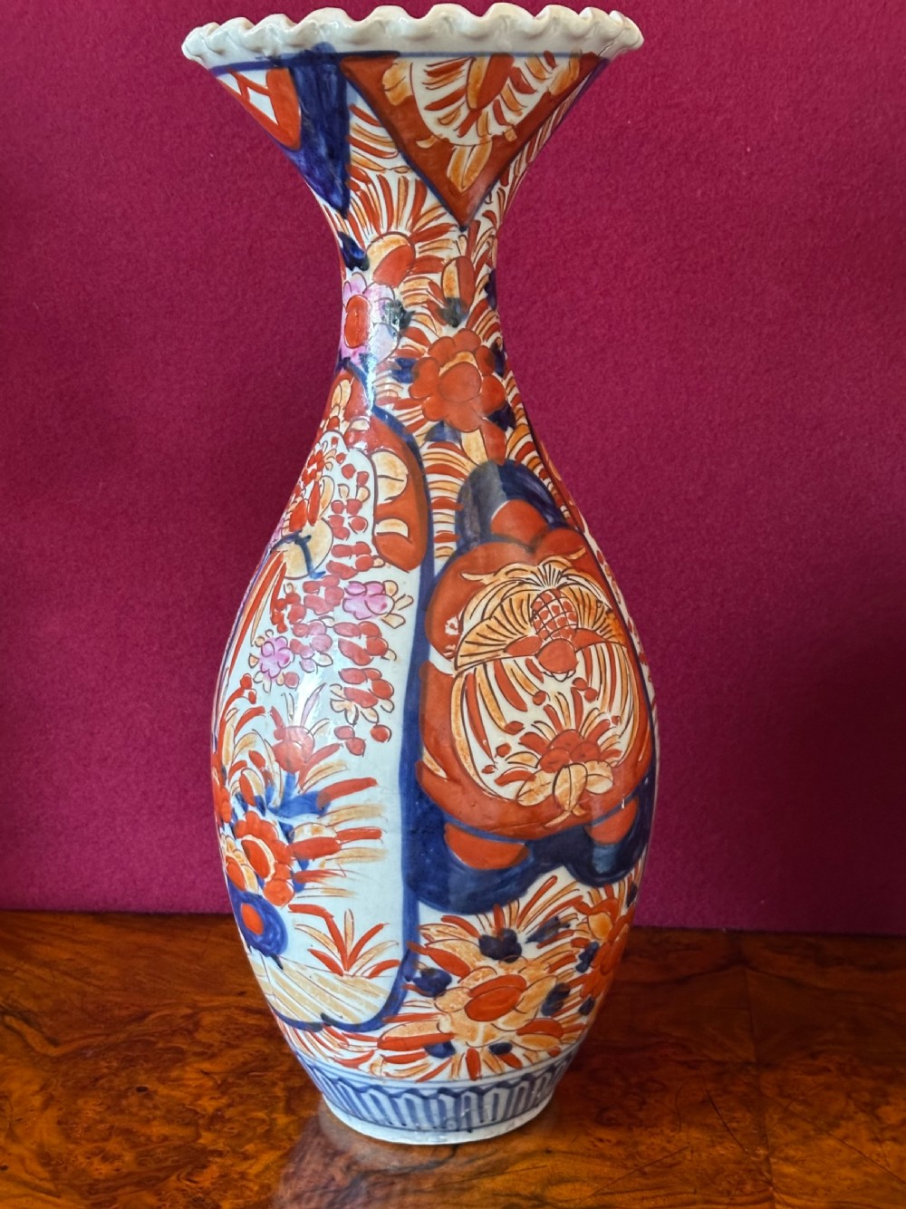 A pair of baluster-shaped Japanese Imari porcelain vases decorated with floral panels in cobalt blue and rust red, featuring crimped scalloped rims. View V