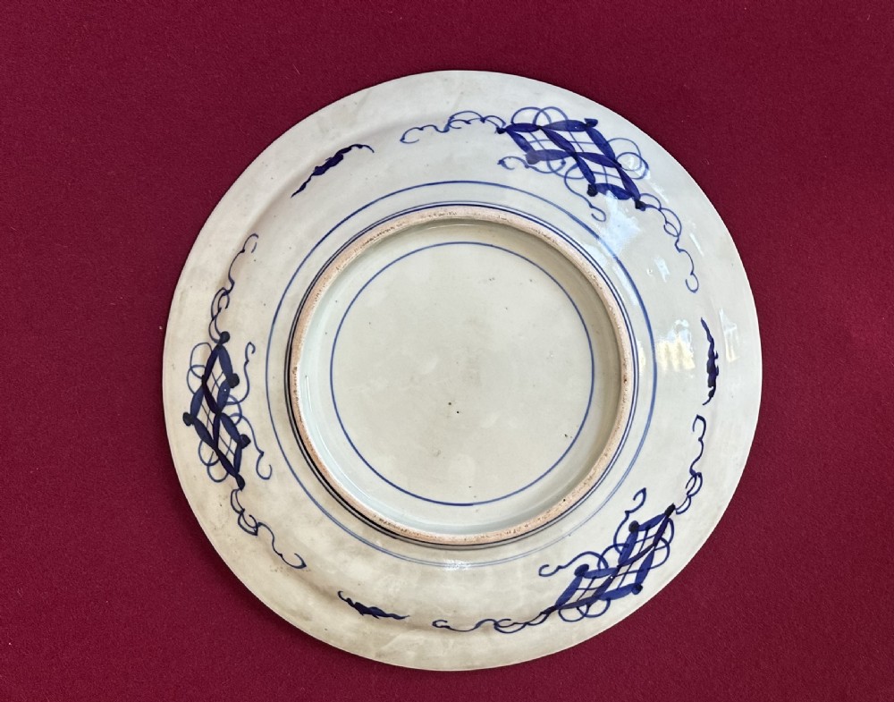 A circular Japanese Imari porcelain charger plate featuring a scalloped edge, central floral motif, and alternating radiated panels of iron-red floral patterns and navy blue gilt detailing. View VI