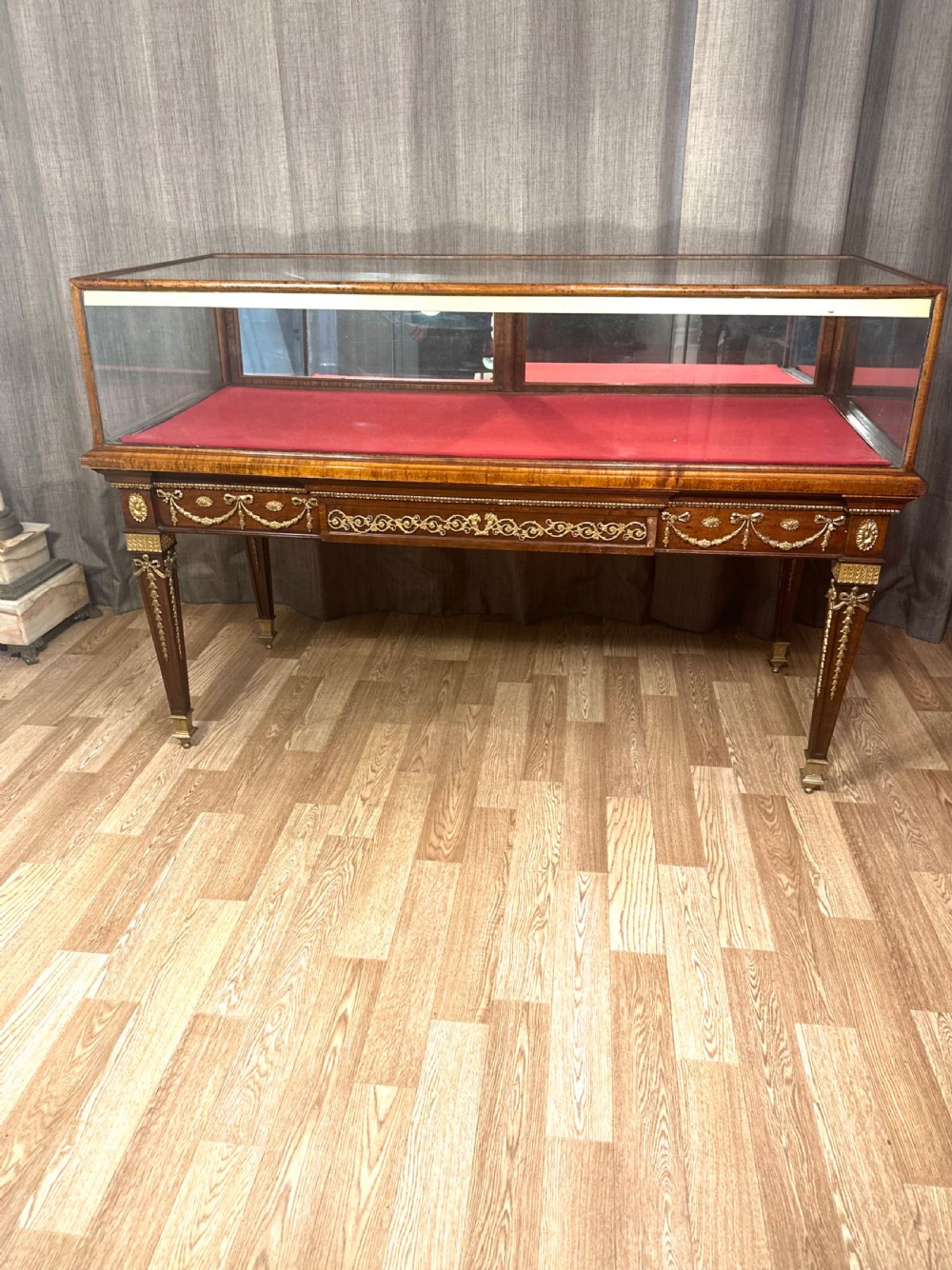 A late 19th-century mahogany table vitrine featuring clear glass panels, a red velvet interior base, tapered legs, and decorative gilt-bronze mounts. View III