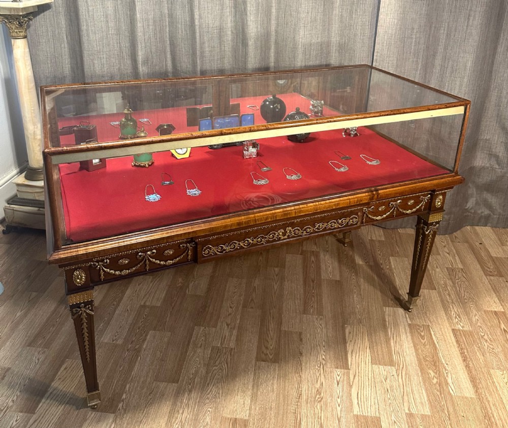 A late 19th-century mahogany table vitrine featuring clear glass panels, a red velvet interior base, tapered legs, and decorative gilt-bronze mounts. View VI