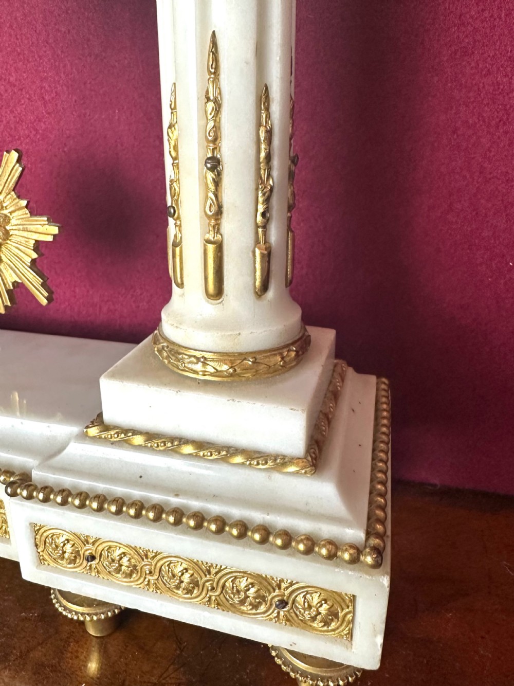 A late 19th-century French three-piece garniture set featuring a central white marble and gilt-bronze portico clock flanked by two matching ornamental urns. View V