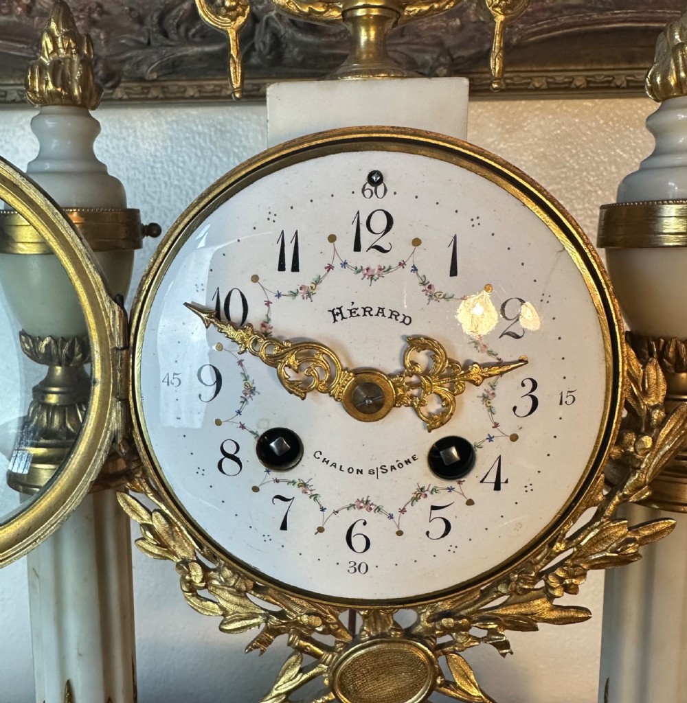 A late 19th-century French three-piece garniture set featuring a central white marble and gilt-bronze portico clock flanked by two matching ornamental urns. View VII