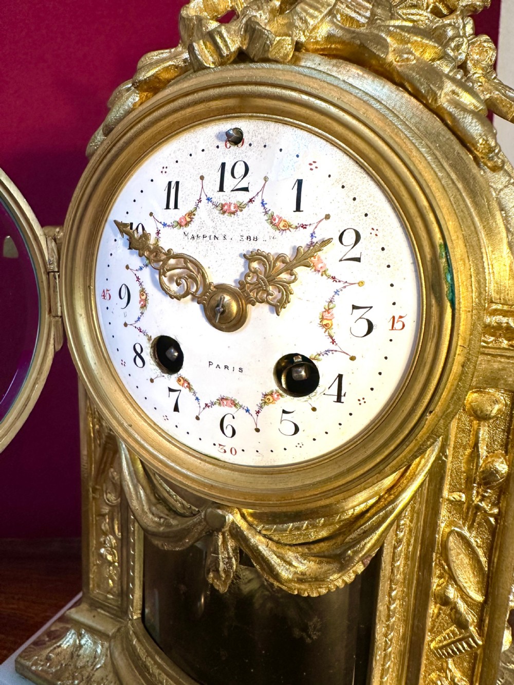 An antique late 19th-century French gilt bronze and white alabaster mantel clock featuring a hand-painted enamel dial, floral swags, and a quiver motif on top. View II