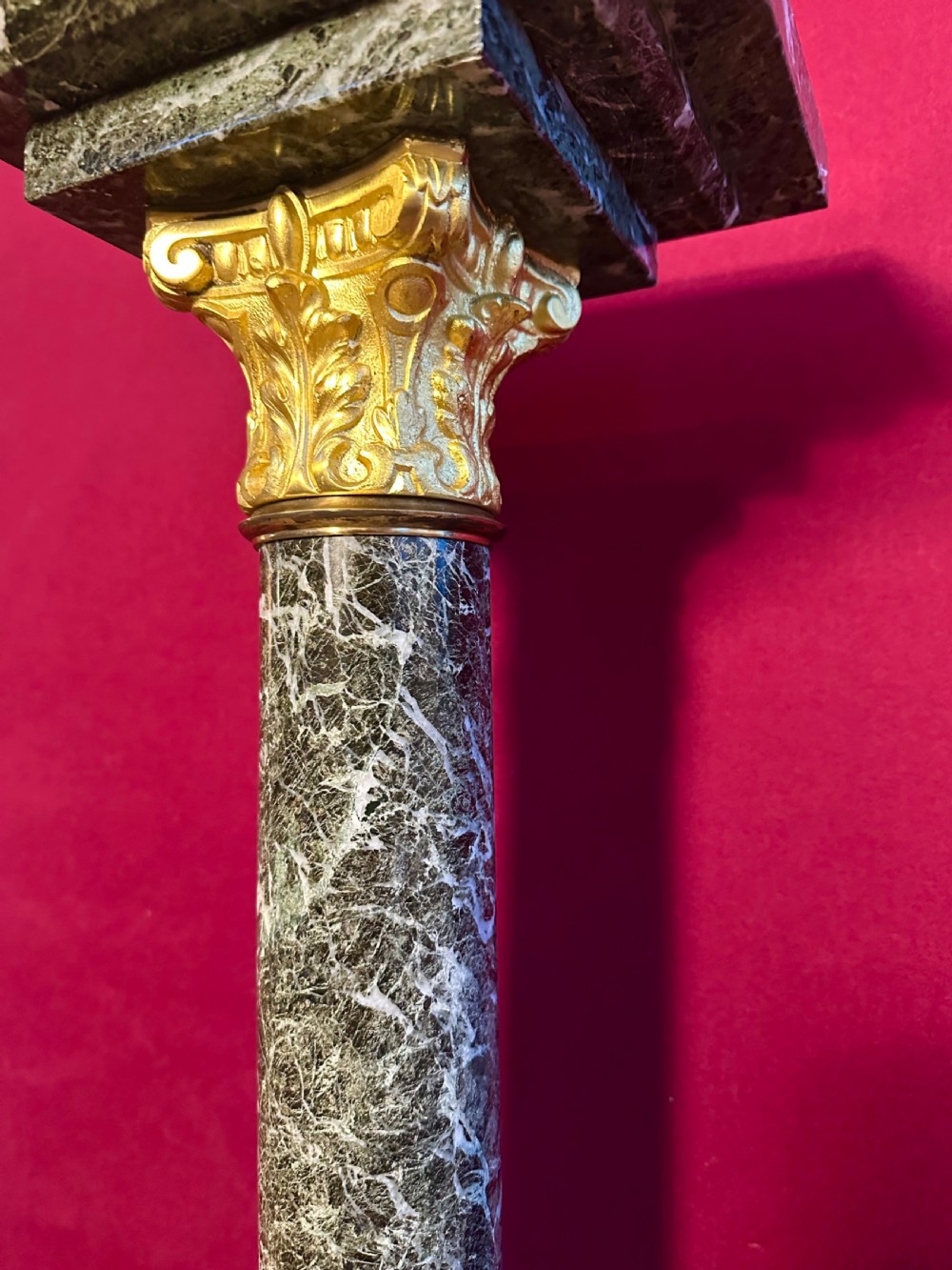 A tall dark green veined marble column pedestal featuring a square top, gilt bronze Corinthian capital, cylindrical shaft, and a stepped square base. View II