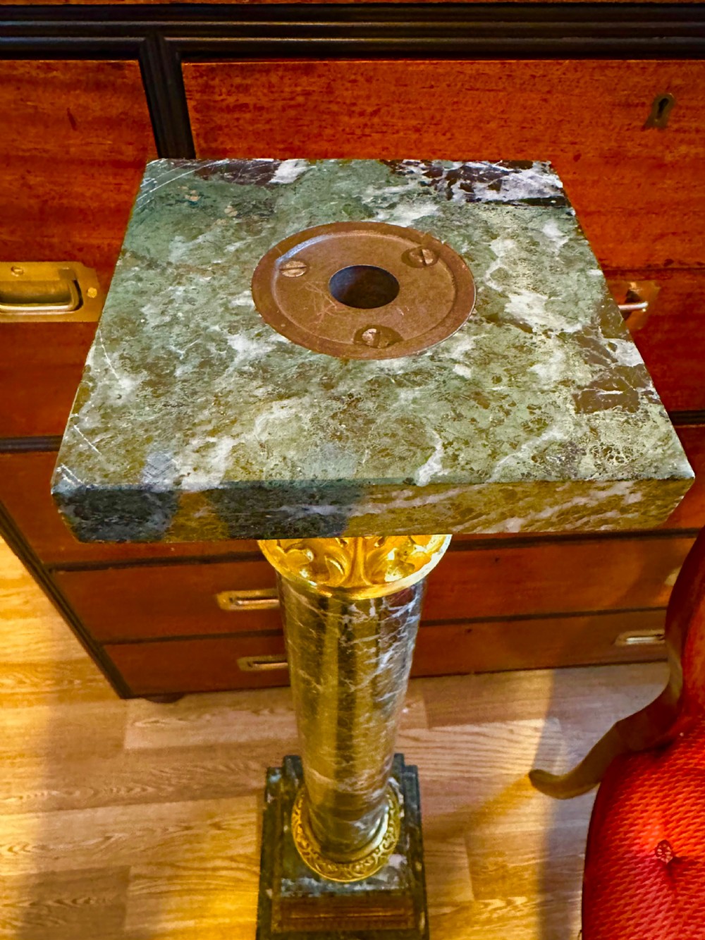 A tall dark green veined marble column pedestal featuring a square top, gilt bronze Corinthian capital, cylindrical shaft, and a stepped square base. View III