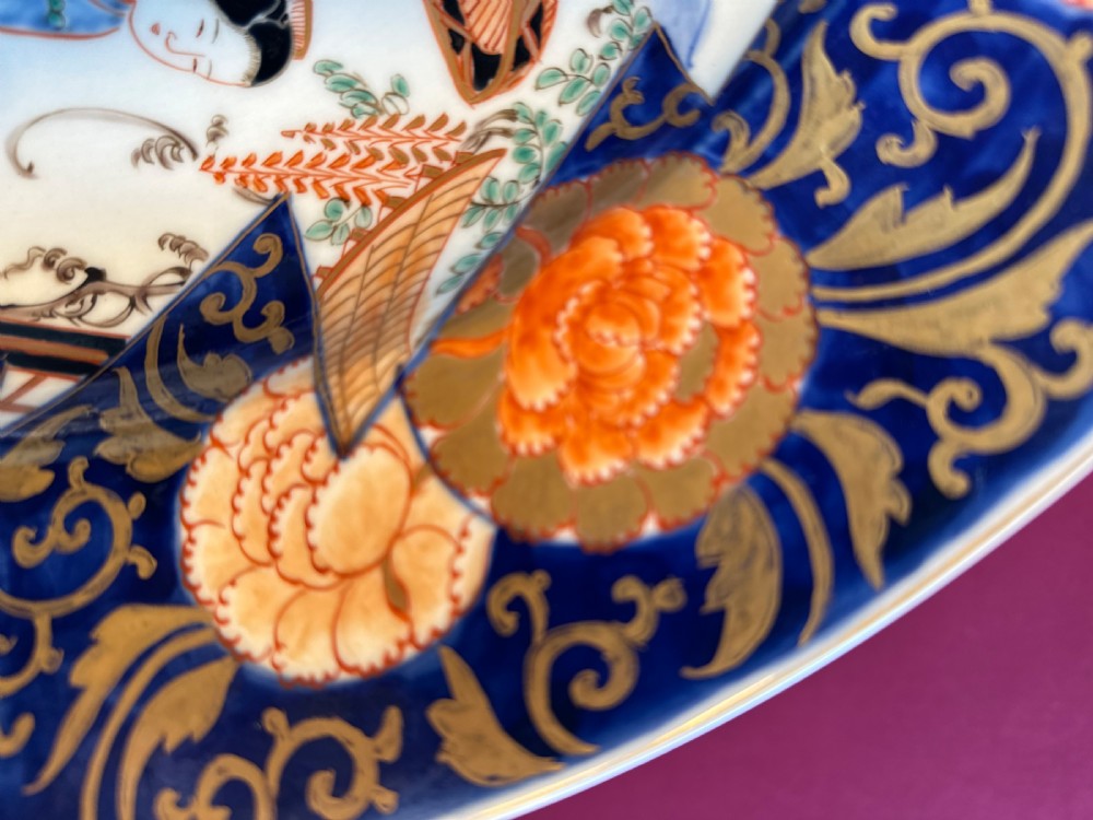 A large circular Japanese Imari porcelain charger featuring hand-painted figures in a landscape surrounded by an ornate cobalt blue and orange floral border. View IV