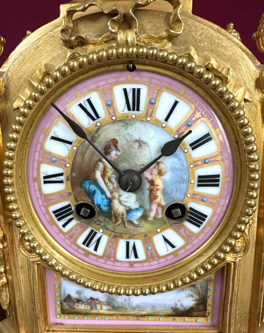 A late 19th-century French gilt bronze mantel clock featuring pink hand-painted porcelain panels and an urn finial. View V