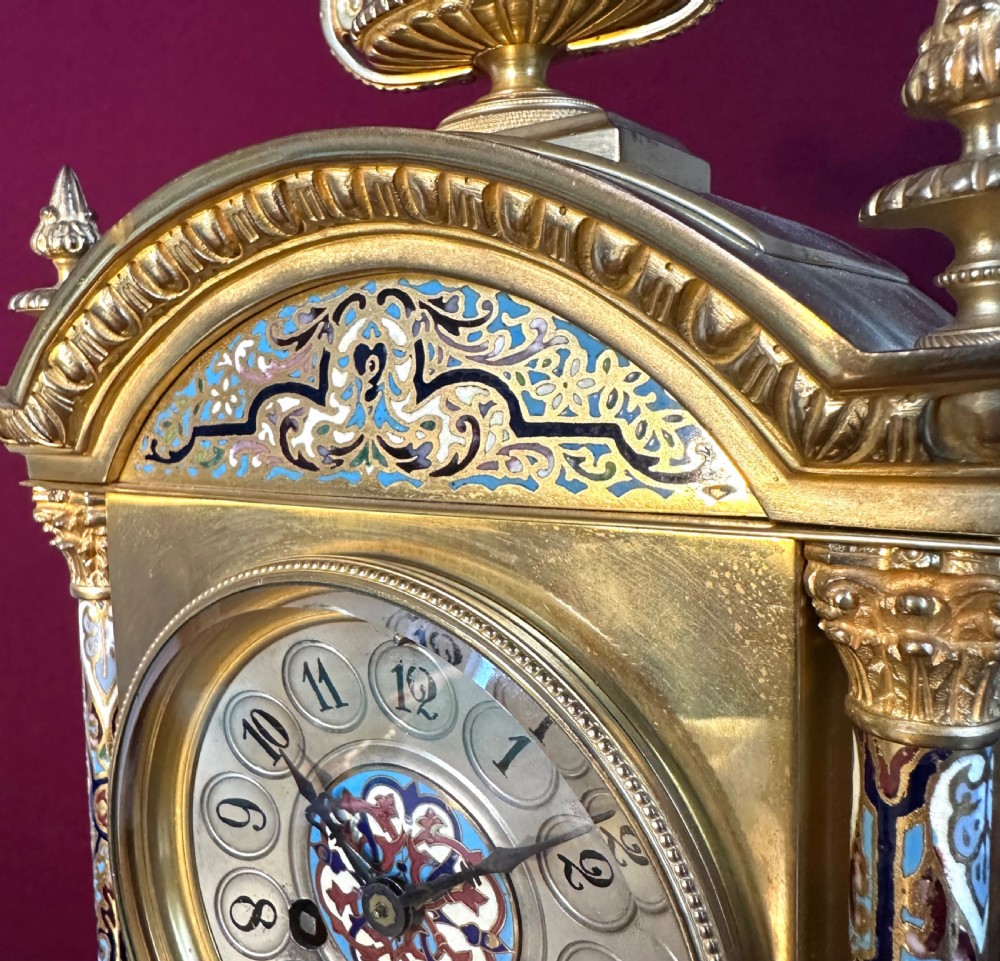 A late 19th-century French gilt-bronze mantel clock decorated with multicoloured champleve enamel scrollwork, columns, and an urn finial. View II
