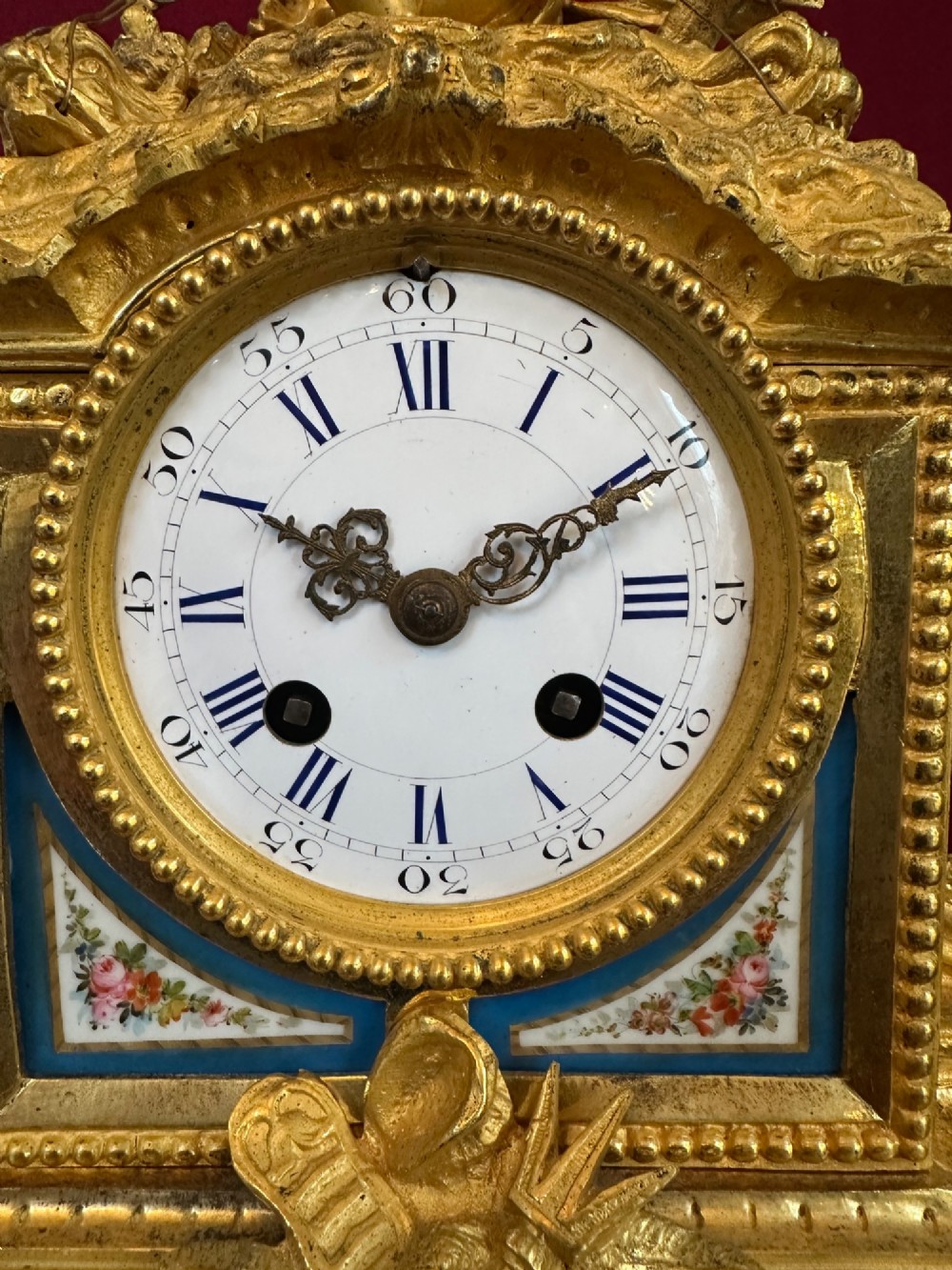 A late 19th-century French gilt bronze mantel clock crowned with a seated cherub figure and featuring an enamel dial with blue porcelain panels. View II
