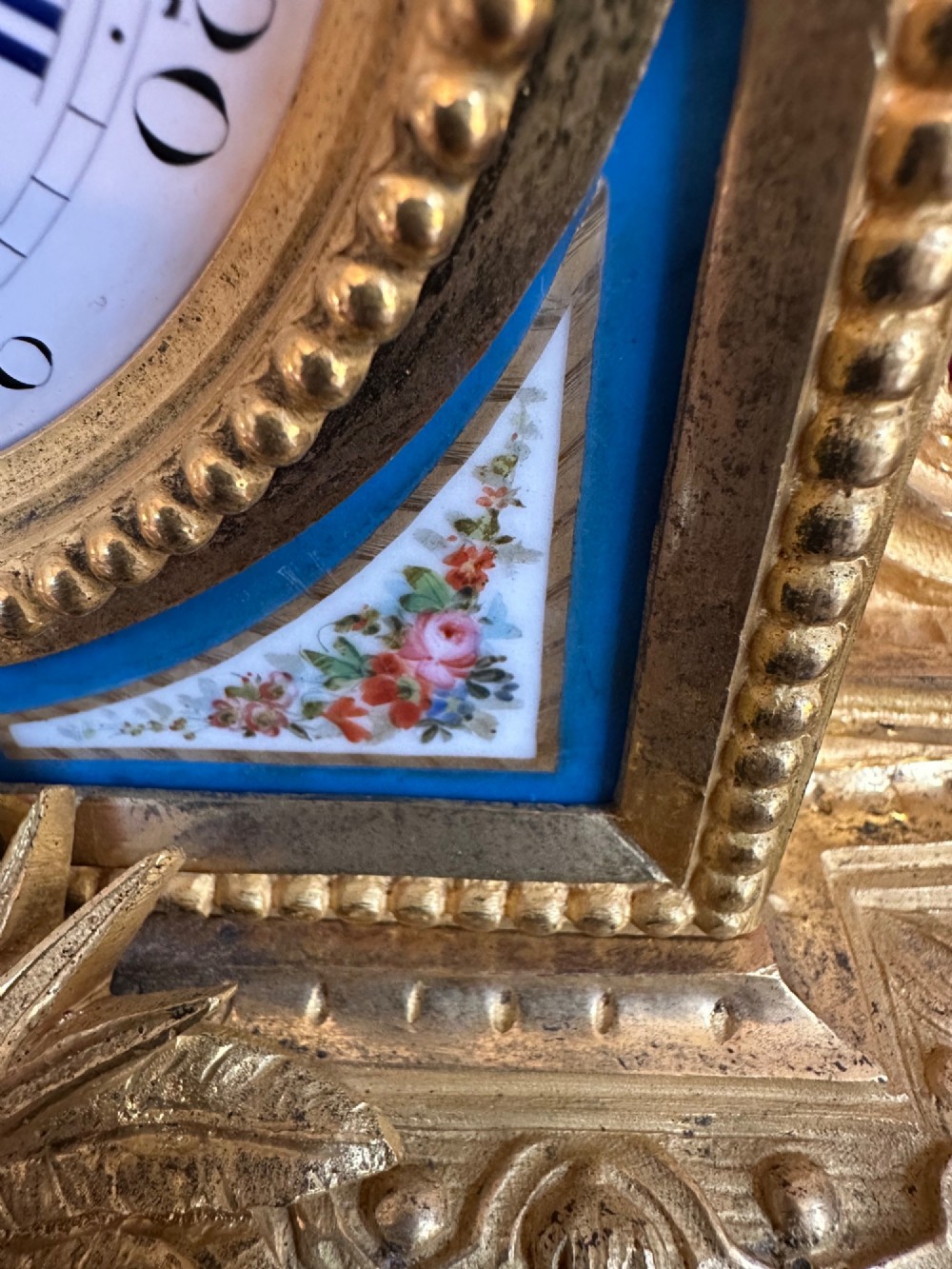 A late 19th-century French gilt bronze mantel clock crowned with a seated cherub figure and featuring an enamel dial with blue porcelain panels. View IV