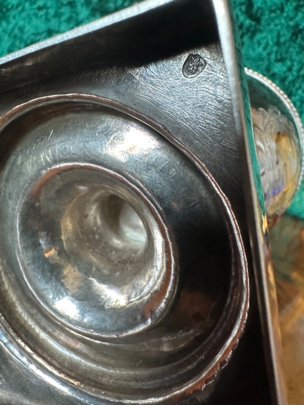 A Georgian silver ewer with an urn-shaped body, engraved heraldic coat of arms, pineapple finial, and a cane-wrapped handle resting on a square base. View V