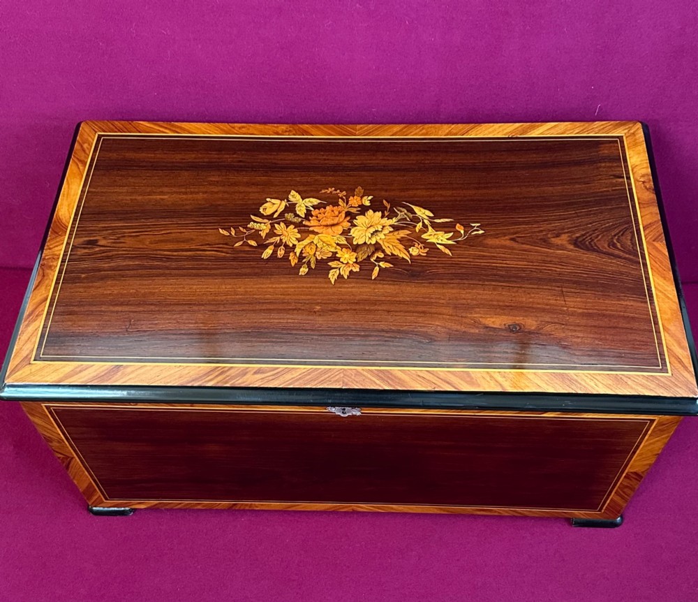 An open Victorian cylinder music box housed in a dark veneered wooden case featuring six exposed bells and an illustrated tune sheet inside the lid. View II