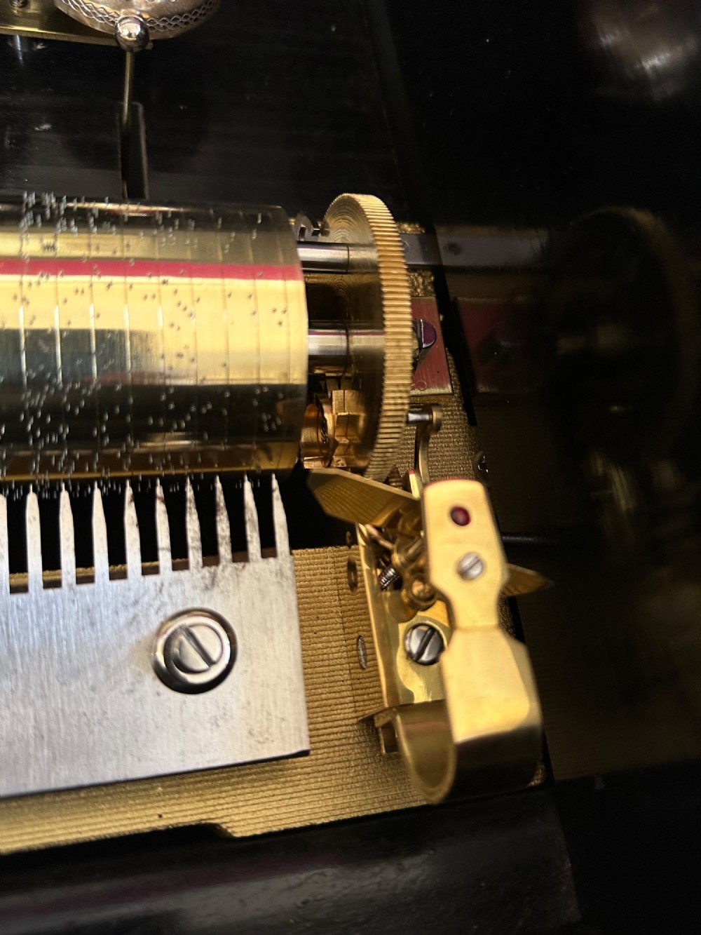 An open Victorian cylinder music box housed in a dark veneered wooden case featuring six exposed bells and an illustrated tune sheet inside the lid. View V