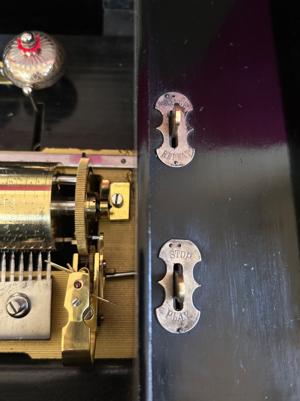 An open Victorian cylinder music box housed in a dark veneered wooden case featuring six exposed bells and an illustrated tune sheet inside the lid. View VI
