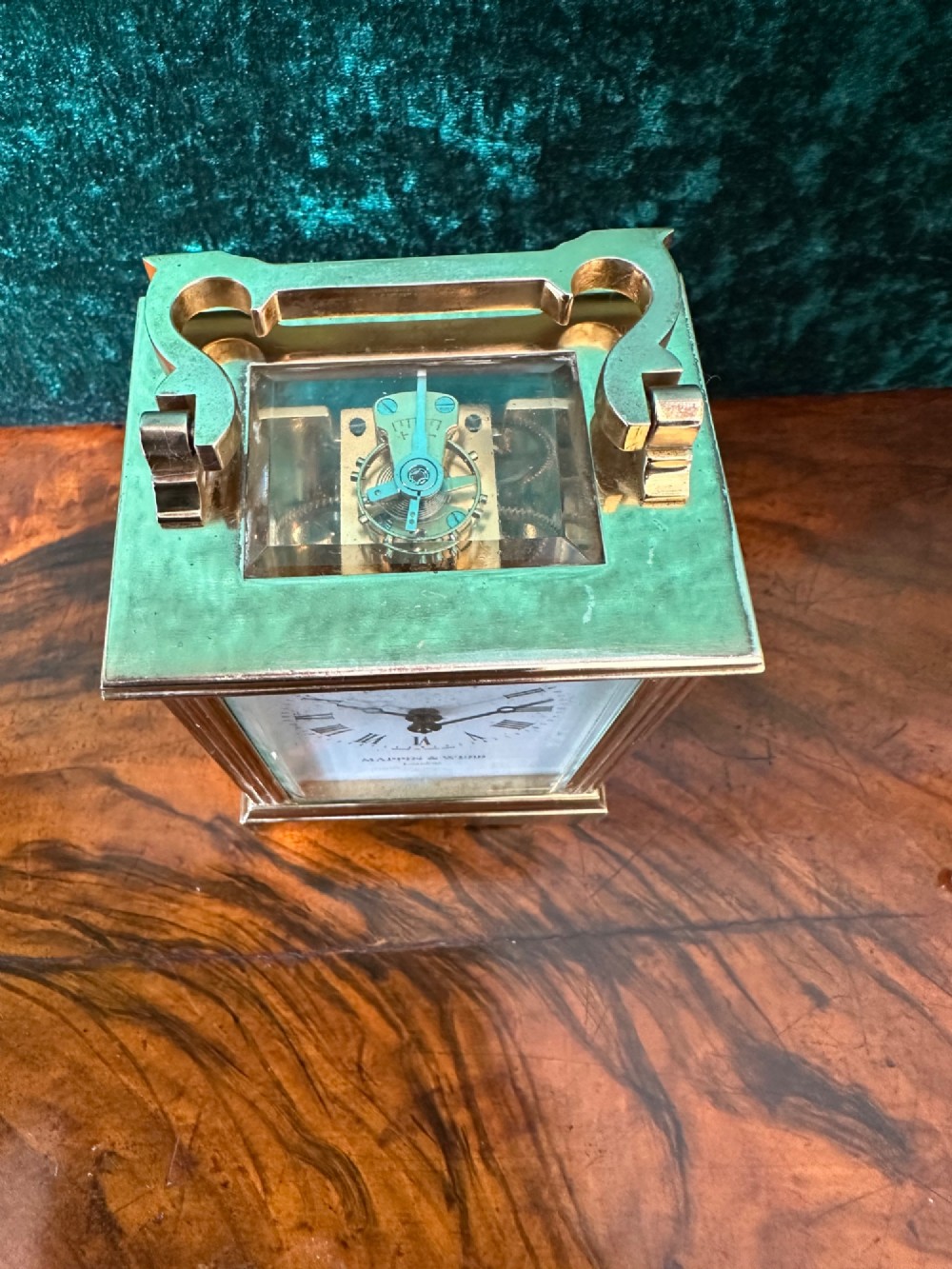 A rectangular brass carriage clock featuring bevelled glass side panels, a top handle, and a white enamel dial with Roman numerals marked Mappin & Webb London. View V