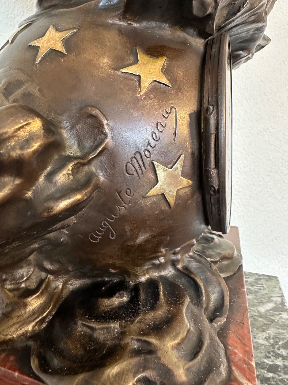 A dark bronze sculpture depicting a draped female figure standing atop a starry globe and mounted on a dark red marble base. View V