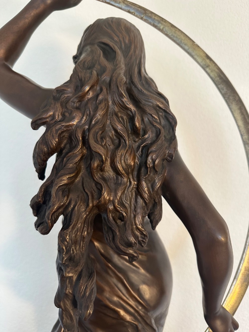 A dark bronze sculpture depicting a draped female figure standing atop a starry globe and mounted on a dark red marble base. View VII
