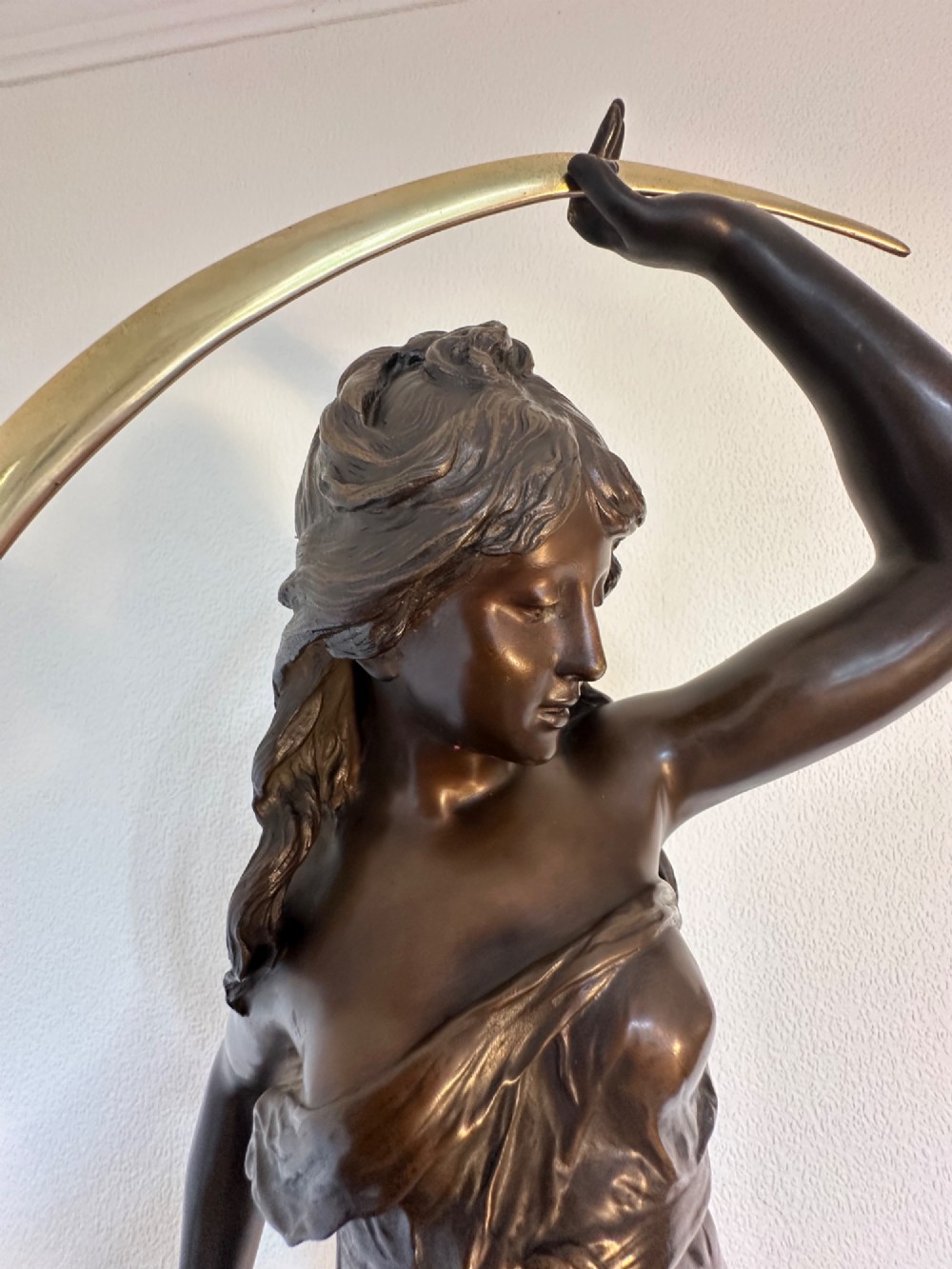 A dark bronze sculpture depicting a draped female figure standing atop a starry globe and mounted on a dark red marble base. View VIII