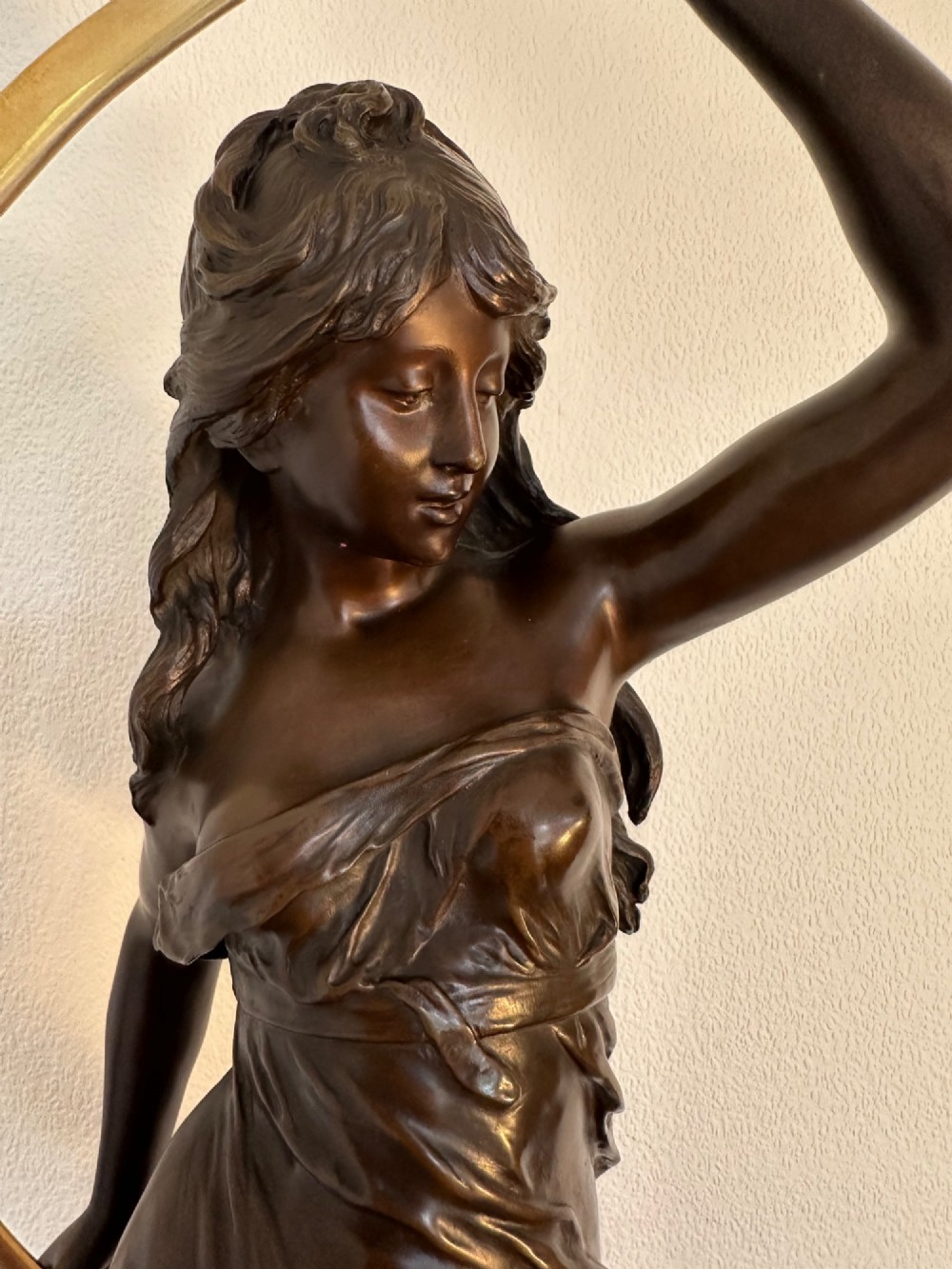 A dark bronze sculpture depicting a draped female figure standing atop a starry globe and mounted on a dark red marble base. View IX