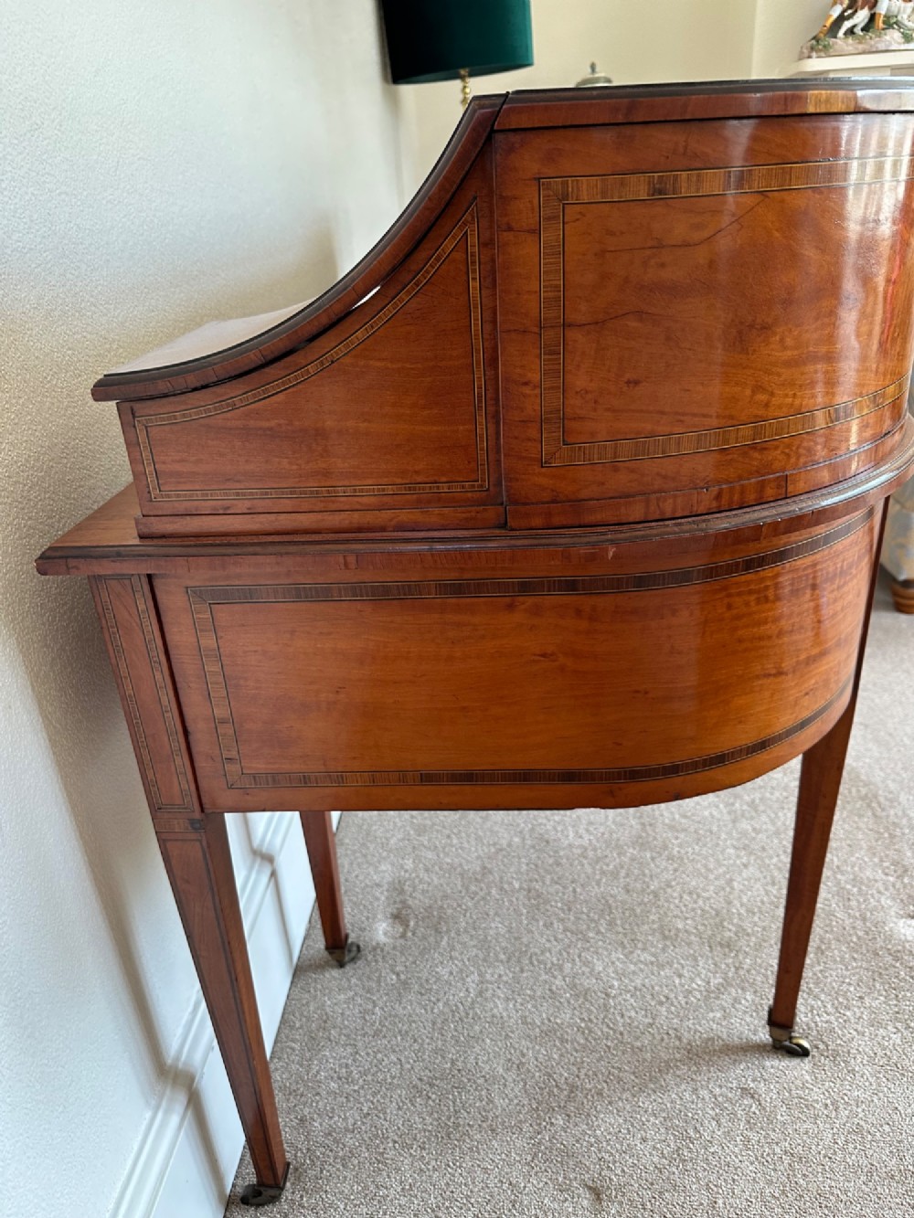 An Edwardian satinwood Carlton House desk featuring a leather writing surface, curved drawer superstructure, and square tapered legs on castors. View VII