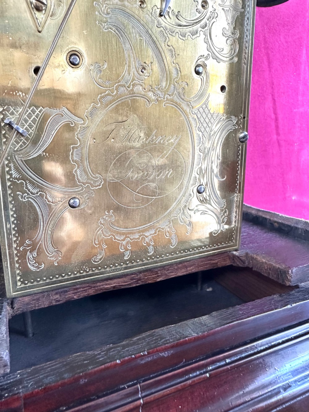 A mid-18th-century Georgian mahogany bracket clock featuring an upper brass carrying handle, an arched glass front door, and an engraved brass dial with a silvered chapter ring. View VI