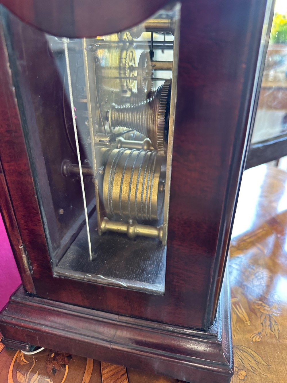 A mid-18th-century Georgian mahogany bracket clock featuring an upper brass carrying handle, an arched glass front door, and an engraved brass dial with a silvered chapter ring. View VII