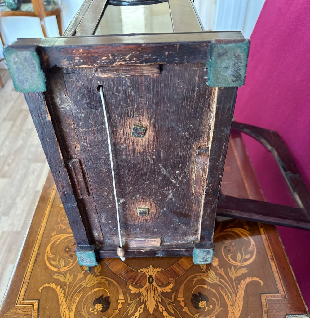 A mid-18th-century Georgian mahogany bracket clock featuring an upper brass carrying handle, an arched glass front door, and an engraved brass dial with a silvered chapter ring. View XI