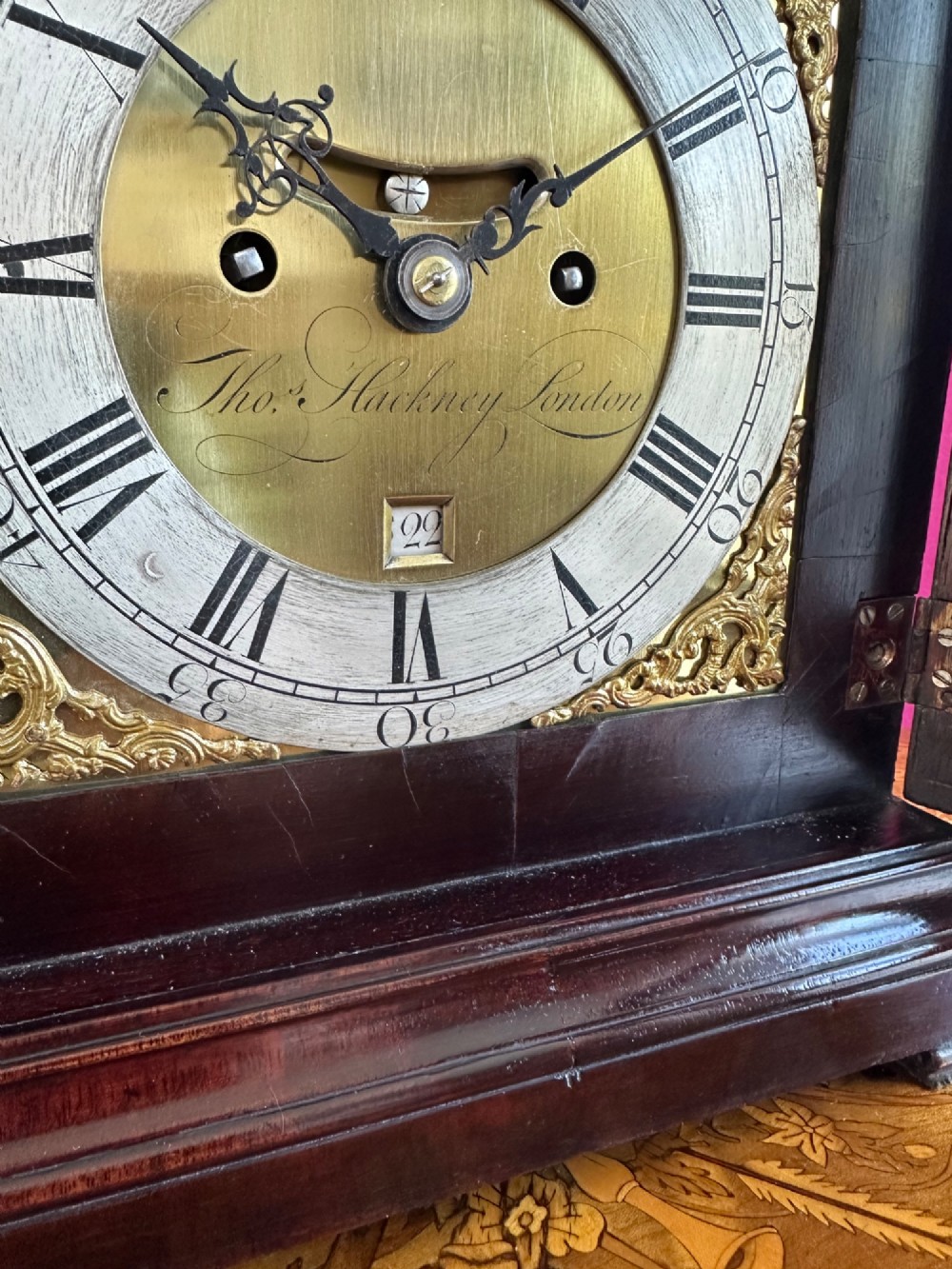 A mid-18th-century Georgian mahogany bracket clock featuring an upper brass carrying handle, an arched glass front door, and an engraved brass dial with a silvered chapter ring. View XIII