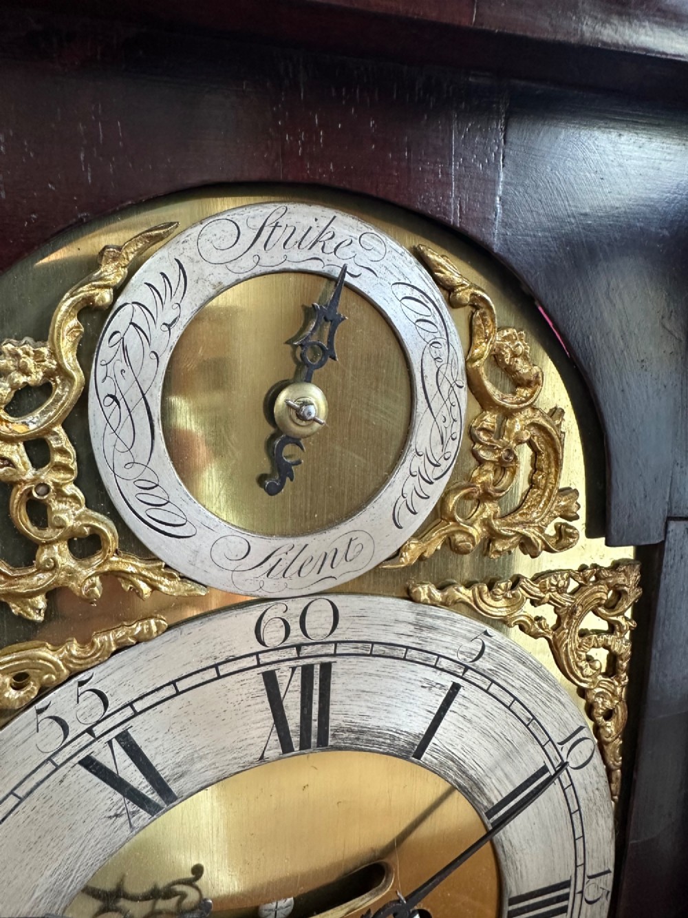 A mid-18th-century Georgian mahogany bracket clock featuring an upper brass carrying handle, an arched glass front door, and an engraved brass dial with a silvered chapter ring. View XIV