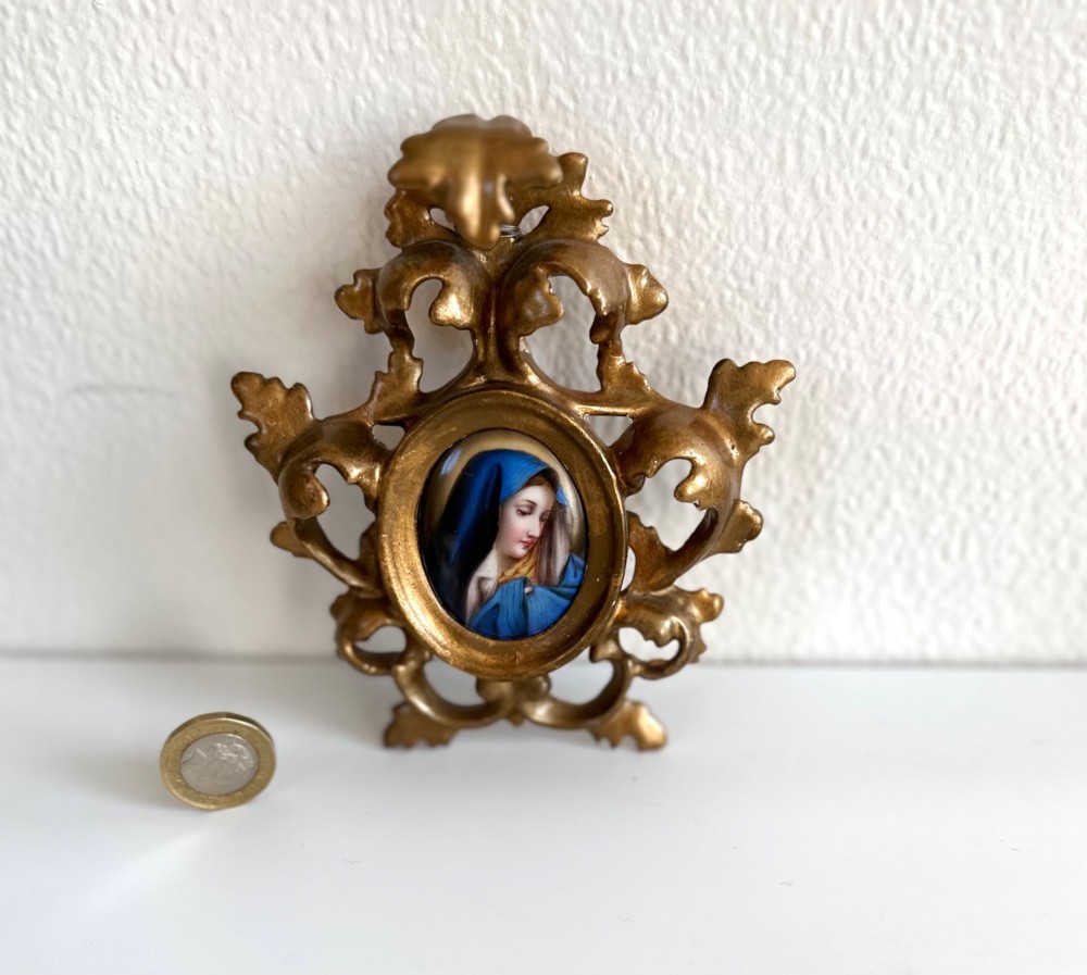 A small Victorian oval miniature portrait of the Madonna in a blue veil, set within a gilt metal scrollwork frame.